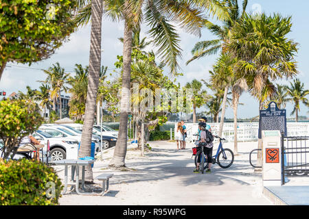 Key West, USA - May 1, 2018: People standing with bikes, bicycles by entrance of Higgs sand beach, African cemetery in Florida keys island city in sun Stock Photo