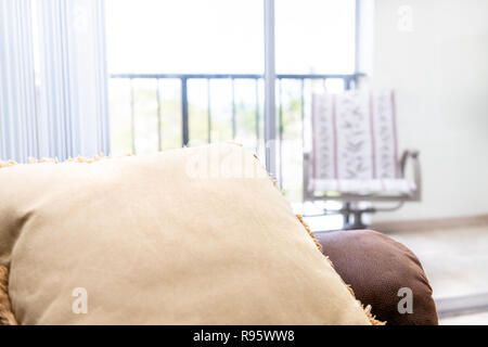 Closeup of brown leather couch with cushion, bright natural light from balcony window in background in house, home apartment living room Stock Photo