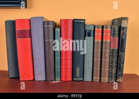 Antique books on old wooden shelf. Old books on yellow and claret background Stock Photo