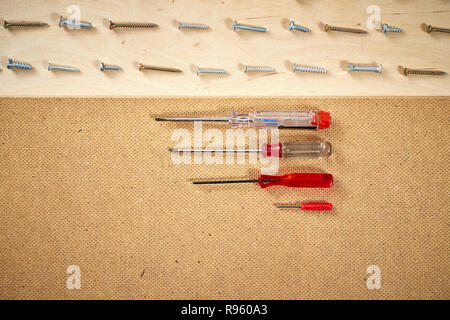 pattern background of various screws and screwdriver on a  wooden work table Stock Photo