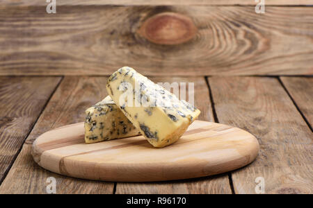 Cheese with blue mold on a cutting board on a wooden background. Close up Stock Photo