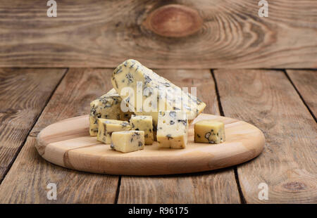 Blue mold cheese and pieces of cheese on a cutting board on wooden background Stock Photo