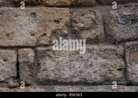 Closeup of an old and weathered wall of a building. The wall seems to be very old and has been weathered due to the age. The worn out bricks are notic Stock Photo
