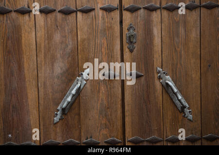Closeup of a locked and closed wooden door is seen on this picture. The design on the door can be seen clearly. It seems the brown colored door is old Stock Photo