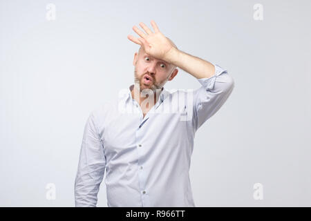 Weary mature man in blue shirt is exhausted with work Stock Photo