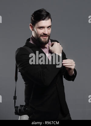 professional photographer with camera, adjusting a cufflink.isolated on grey background Stock Photo