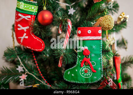 Young woman decorating Christmas tree with toys at home, wearing winter sweater. Preparing to New year. Closeup of reindeer Stock Photo