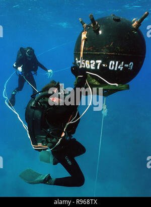 A U.S. Navy diver attaches an inert satchel charge to a training mine, during training exercises in waters off Naval Base Guantanamo Bay, Cuba. DoD photo by Petty Officer 2nd Class Andrew McKaskle, U.S. Navy. Stock Photo