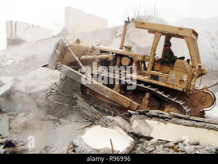 A U.S. Navy Seabee operates a bulldozer to demolish an unsafe building in Muzaffarabad, Pakistan. The Department of Defense is supporting the US State Department and provided disaster relief supplies and services following the massive earthquake that struck Pakistan and parts of India and Afghanistan.  DoD photo by Petty Officer 2nd Class James Godown, U.S. Navy Stock Photo