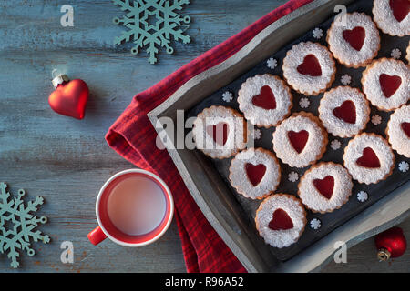 Top view of traditional Linzer cookies with red jam heart on dark background. Christmas or Valentine traditional tasty snack. Stock Photo