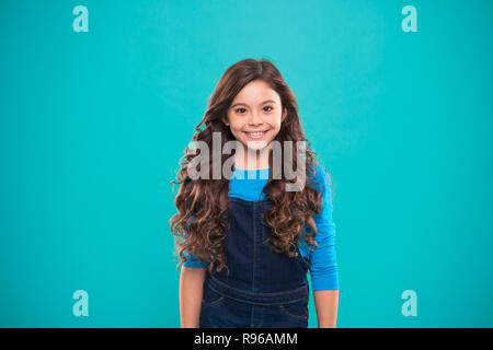 Extreme hair volume. Kid girl long healthy shiny hair. Little girl grow long hair. Teaching healthy hair care habits. Kid happy cute face with adorable curly hairstyle stand over blue background Stock Extreme hair volume. Kid girl long healthy shiny hair. Little girl grow long hair. Teaching healthy hair care habits. Kid happy cute face with adorable curly hairstyle stand over blue background Stock