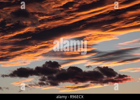 Clouded orange and grey sky right after the sun had set behind the horizon. A telephoto detail. Stock Photo