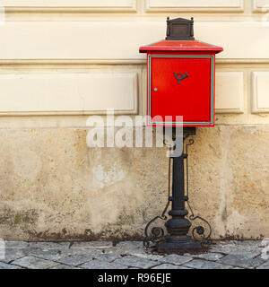 Traditional red mailbox on black wrought iron stand in the Main square of Sopron, Hungary. Stock Photo