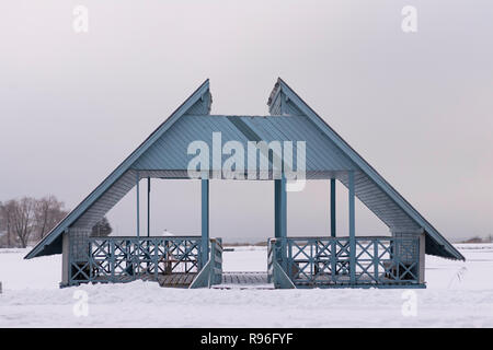 wooden bluish deck standing on a frozen sea water at the beach serrounnded with lots of snow Stock Photo