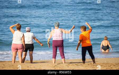 Elderly women stretching on beach during keep fit class in Spain Stock Photo