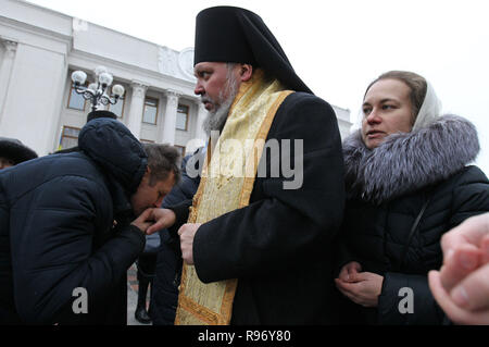 Kiev, Kiev, Ukraine. 20th Dec, 2018. Ukrainian believer seen kissing the hand of a priest while praying next to the Ukrainian Parliament during the demonstration.Believers protest against change of name of the Ukrainian Orthodox Church of Moscow Patriarchate. Ukrainian Parliament voted the draft law according to which the Ukrainian Orthodox Church of Moscow Patriarchate should change name and indicate its affiliation with Russia. Credit: Pavlo Gonchar/SOPA Images/ZUMA Wire/Alamy Live News Stock Photo