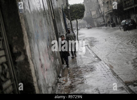 Palestinians are seen walking on a street flooded during a heavy rainfall at the Jabalya refugee camp in Gaza Strip. Stock Photo