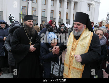 Ukrainian believer seen kissing the hand of a priest while praying next to the Ukrainian Parliament during the demonstration. Believers protest against change of name of the Ukrainian Orthodox Church of Moscow Patriarchate. Ukrainian Parliament voted the draft law according to which the Ukrainian Orthodox Church of Moscow Patriarchate should change name and indicate its affiliation with Russia. Stock Photo