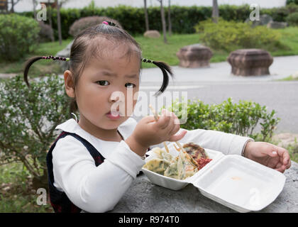Young girl in cute pigtails eating lunch, Bao garden, Huizhou Ancient City, Huangshan, Anhui, China Stock Photo