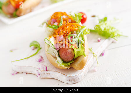 Hot dog with  cucumber, carrot, tomato and lettuce on wooden background. Fast food menu. Stock Photo