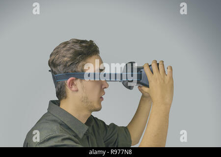 Young man in a shirt uses virtual reality glasses on the light grey background Stock Photo