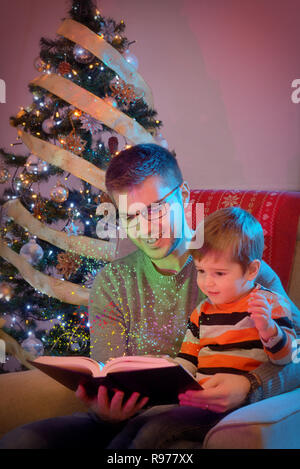 Father and son reading book together on chair Stock Photo