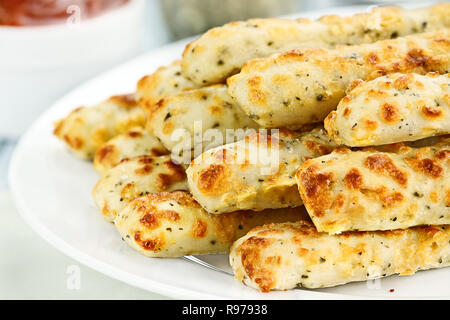 Fresh golden, cheesy breadsticks with marinara sauce and parmesan cheese in background. Shallow depth of field. Stock Photo