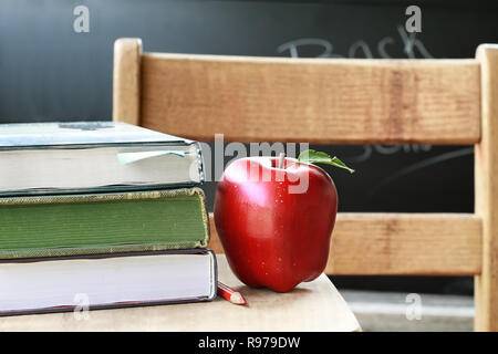 School books with apple and pencil on desk. Stock Photo