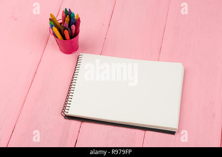 Blank note pad and crayons on pink wooden table Stock Photo