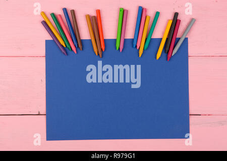 Blank blue paper and crayons on pink wooden table Stock Photo