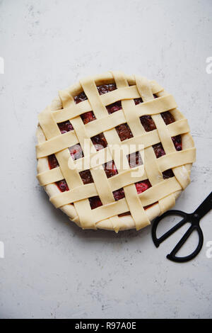 Uncooked berry pie with a lattice decoration on top. Concrete background, cooking process. Stock Photo