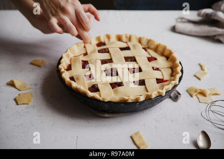 Uncooked berry pie with a lattice decoration on top. Concrete background, cooking process. Stock Photo