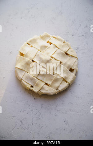 Uncooked apple pie with a wide lattice on top. Concrete background, preparation process. Stock Photo