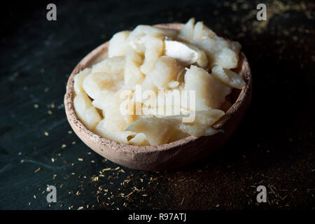 closeup of some desalinated strips of salt cod in a rustic earthenware bowl, on a dark green table, the main ingredient to prepare the catalan xato, a Stock Photo