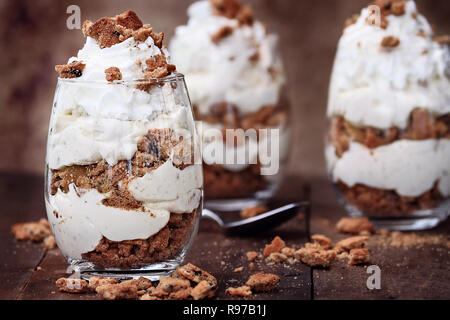 Three glasses of crumbled chocolate chip cookies and cheesecake parfaits against a rustic background. Extreme shallow depth of field with selective fo Stock Photo
