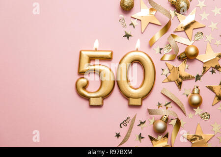 Number 50 gold celebration candle on star and glitter background Stock Photo