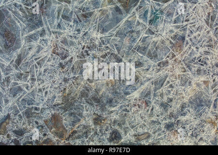 Frozen water in shallow water. Round stones among many sharp icicles as background. Toned image Stock Photo