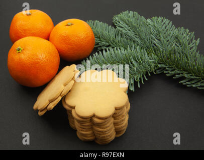 Ginger cookies, fir branches and tangerines, on a dark background Stock Photo