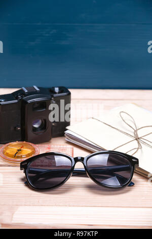 Sunglasses, compass, bunch of letters and an old film camera on light and blue wooden background. Copy space at the top. Concept of summer travel dest Stock Photo