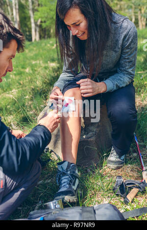 Man healing knee to woman who has been injured trekking Stock Photo