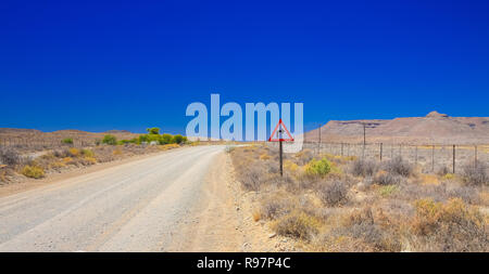 Desert landscape view of a sharp left turn sign on a dirt road in the Karoo of South Africa Stock Photo
