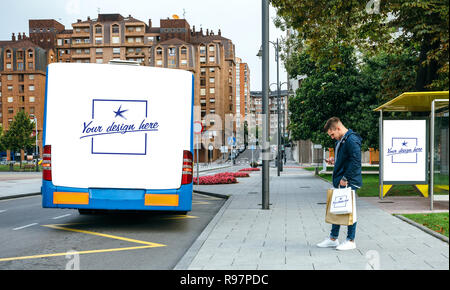 Man waiting bus looking mobile. Customizable bus, bag and canopy Stock Photo