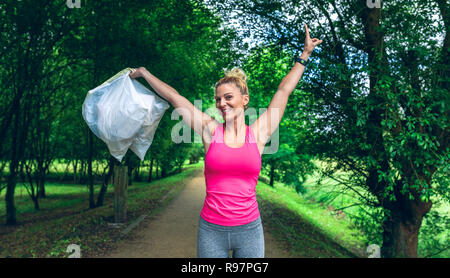 Girl arms up showing garbage bags doing plogging Stock Photo