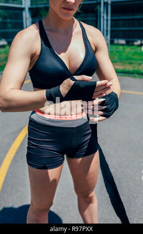 Sportswoman putting on boxing bandages