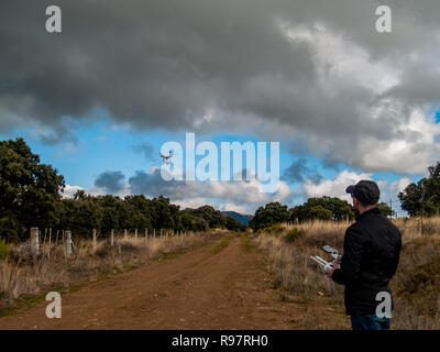 A drone pilot piloting with the remote control with smartphone in his hands in the forest Stock Photo