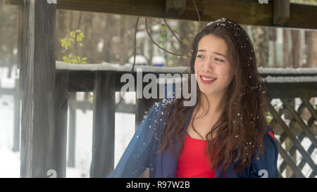 Young asian teen with red dress standing in snow and smiling Stock Photo