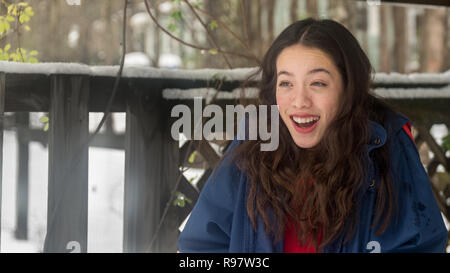 Young asian teen with red dress standing in snow surprised and smiling Stock Photo