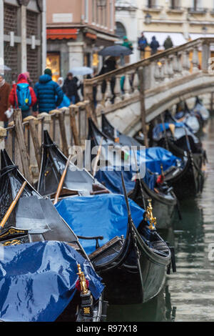 Parked gondolas at side canal at rainy day in Venice, Italy