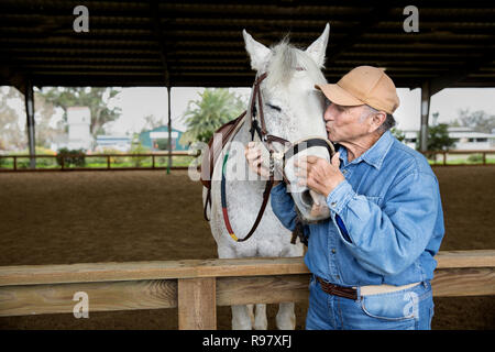 Senior man kissing his horse Stock Photo