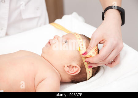 Close-up shot of pediatrician examines two months baby boy. Doctor using measurement tape checking baby head size Stock Photo